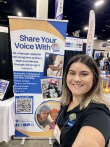 Photo of a girl taking a selfie in front of Rare Patient Voice's new conference sign.